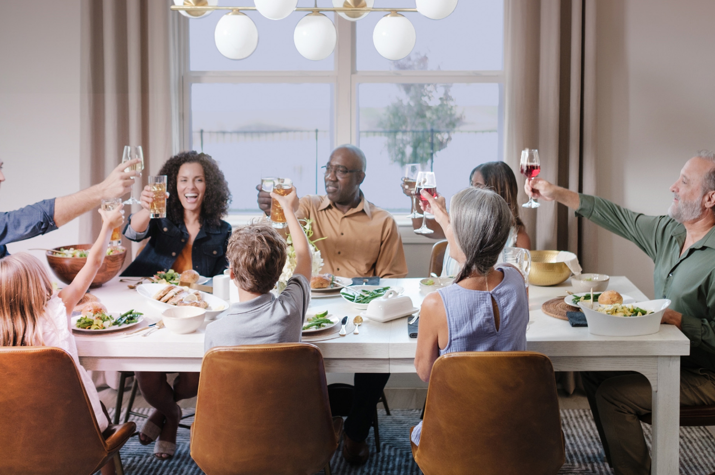 friends family and children raising a glass in a toast at their dining room table