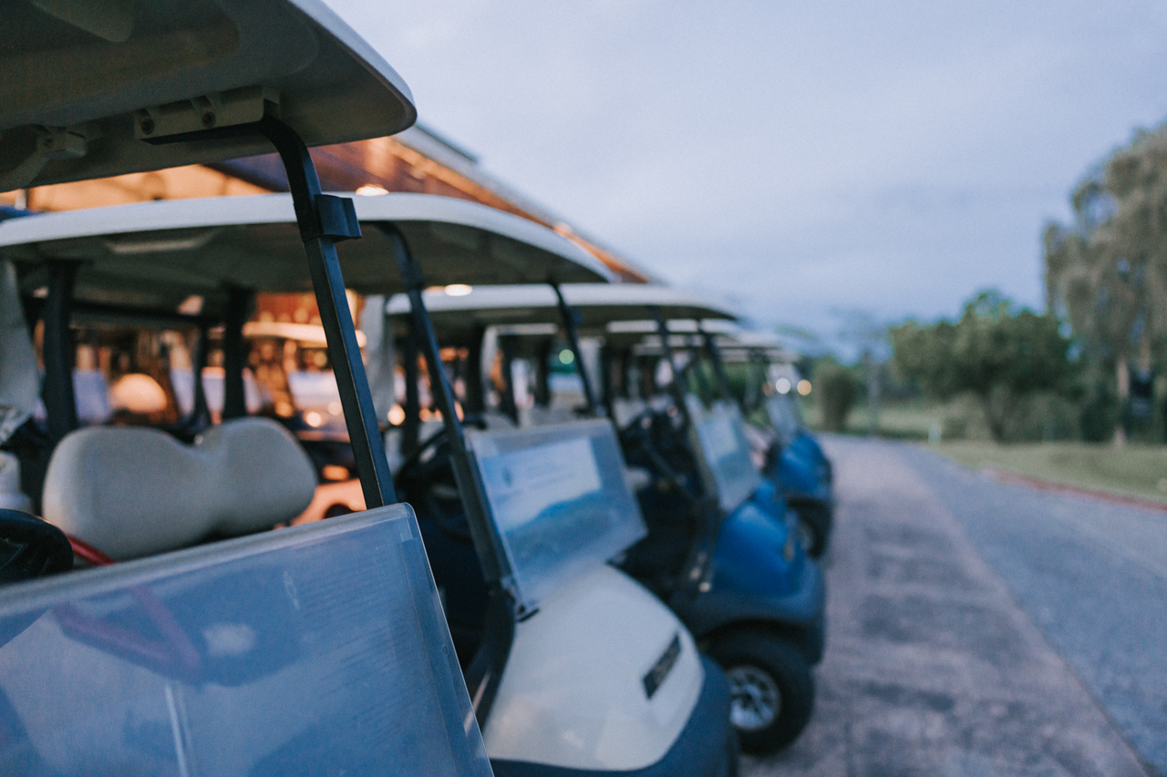 A line of parked golf carts at dusk