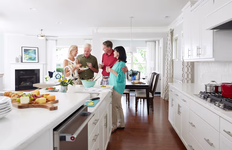 two couples socializing with food around a kitchen island