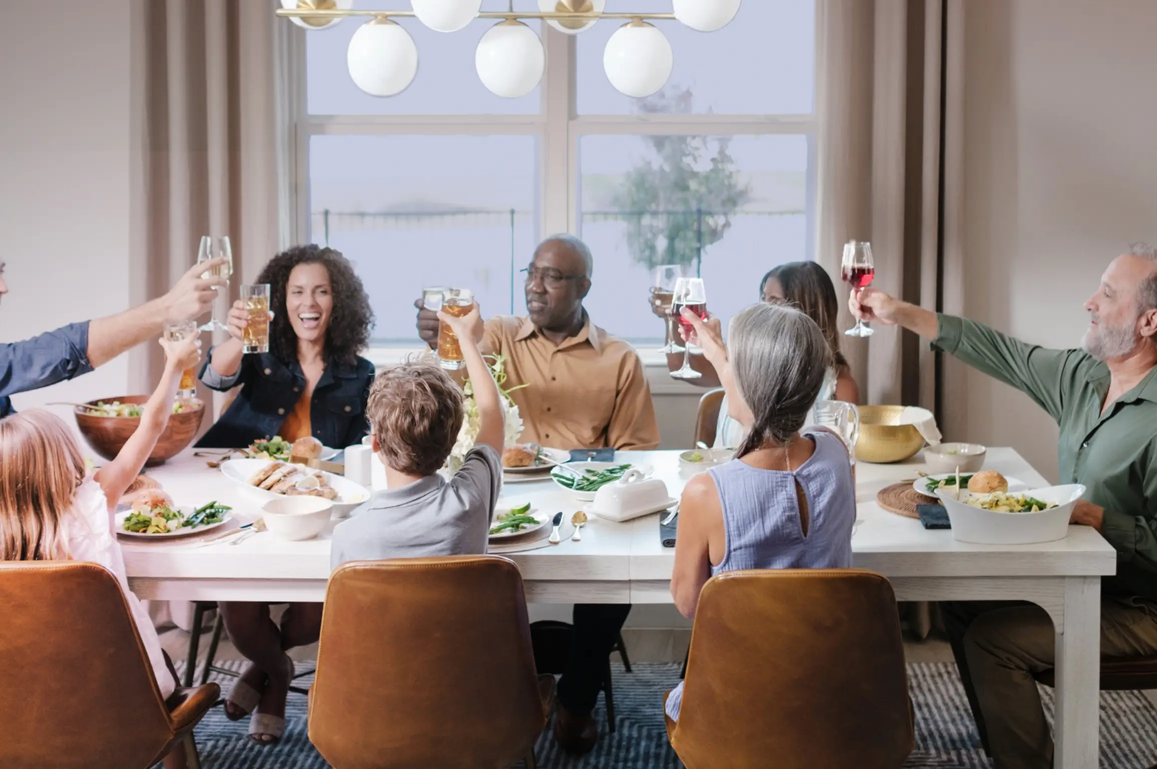 friends family and children raising a glass in a toast at their dining room table