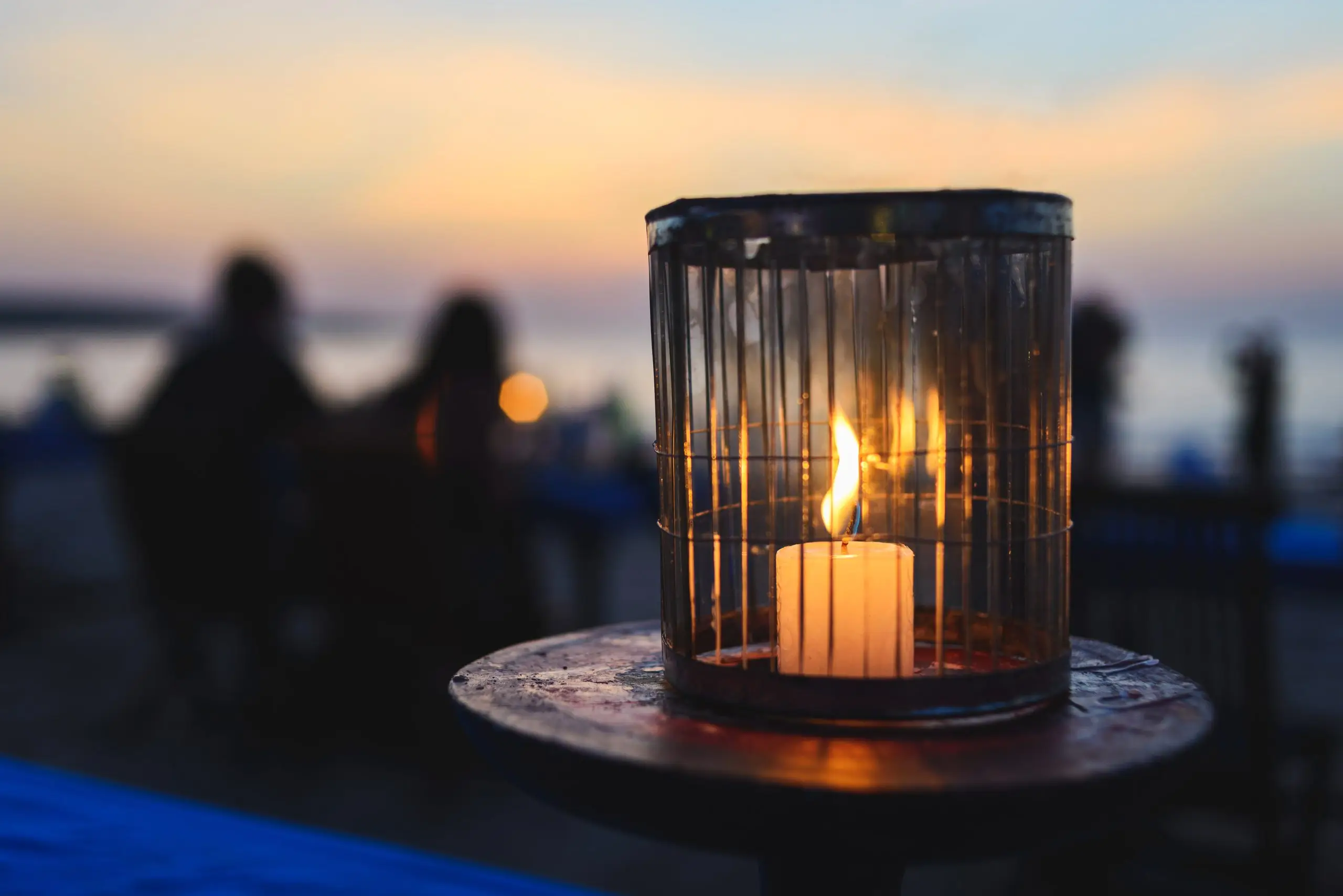 Romantic dinner in a cafe on the ocean by sunset. A candle burns on a table for guests in a cafe. Travel and enjoy your holiday on the beach. Soft focus, beautiful bokeh.