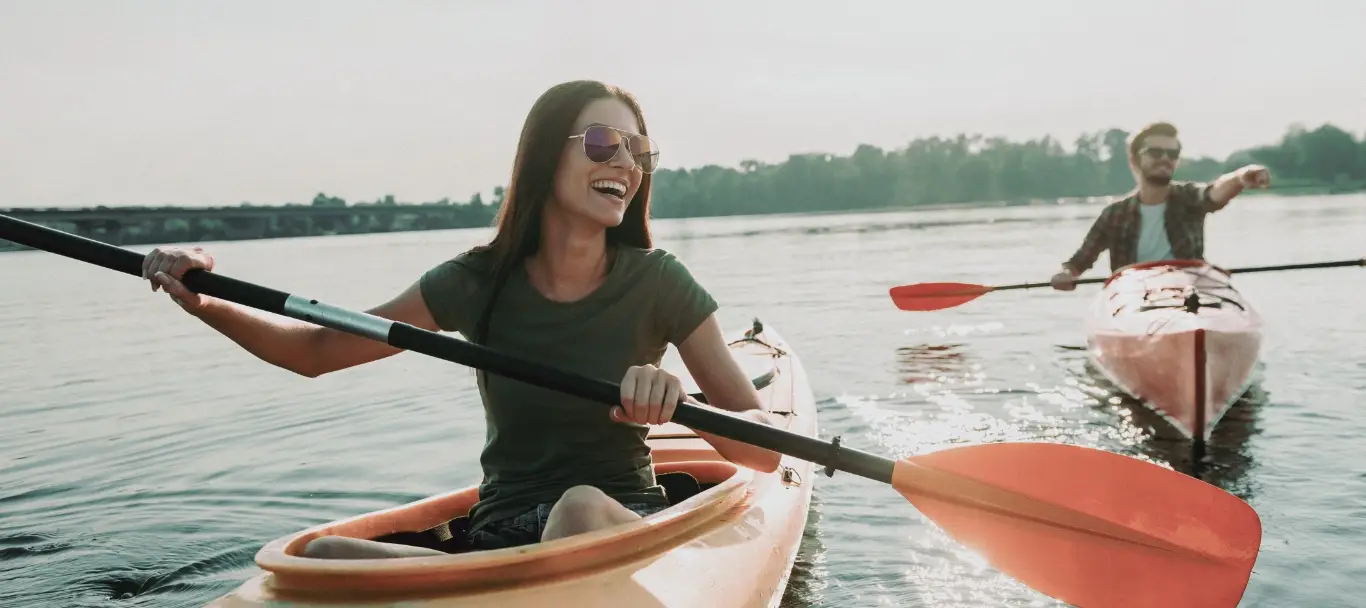 Beautiful young couple kayaking on lake together and smiling
