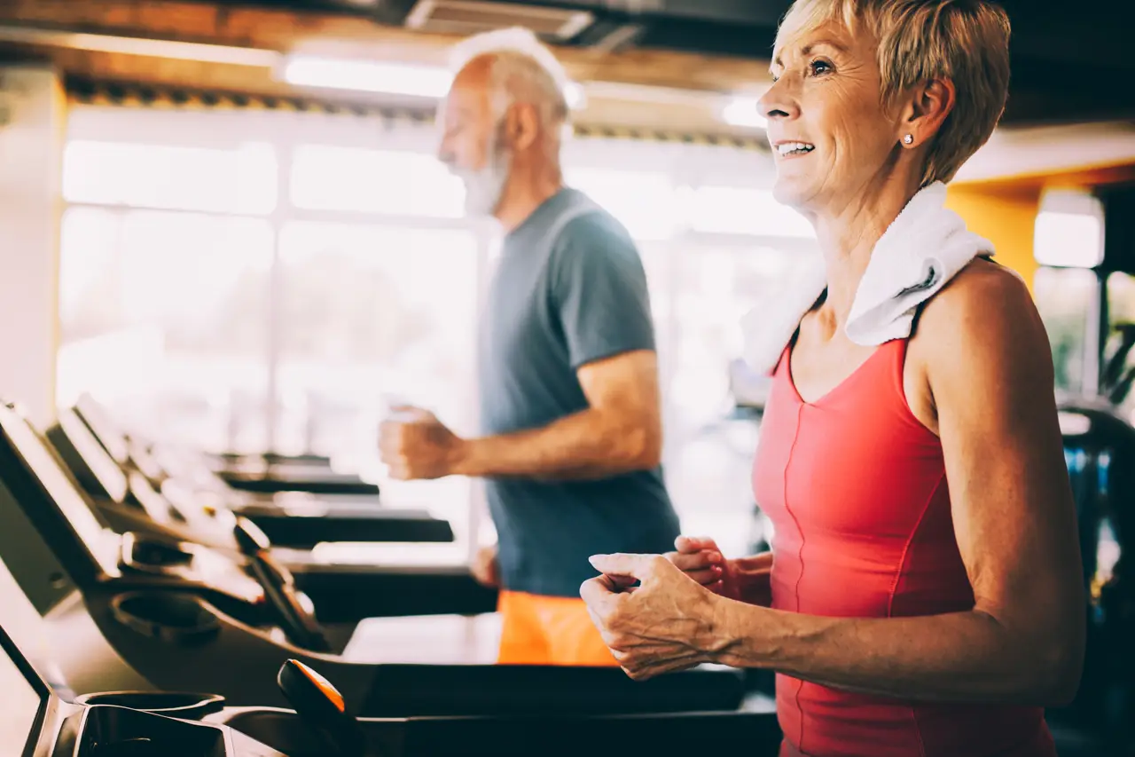 Mature people running in machine treadmill at fitness gym club