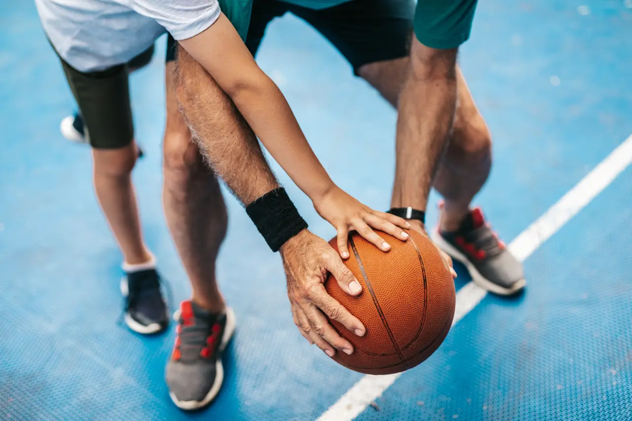 Grandfather and his grandson enjoying and playing together on basketball court.