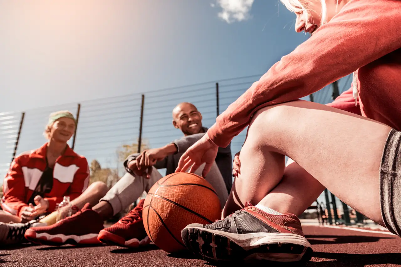 Basketball ball lying on the court near positive young people talking to each other