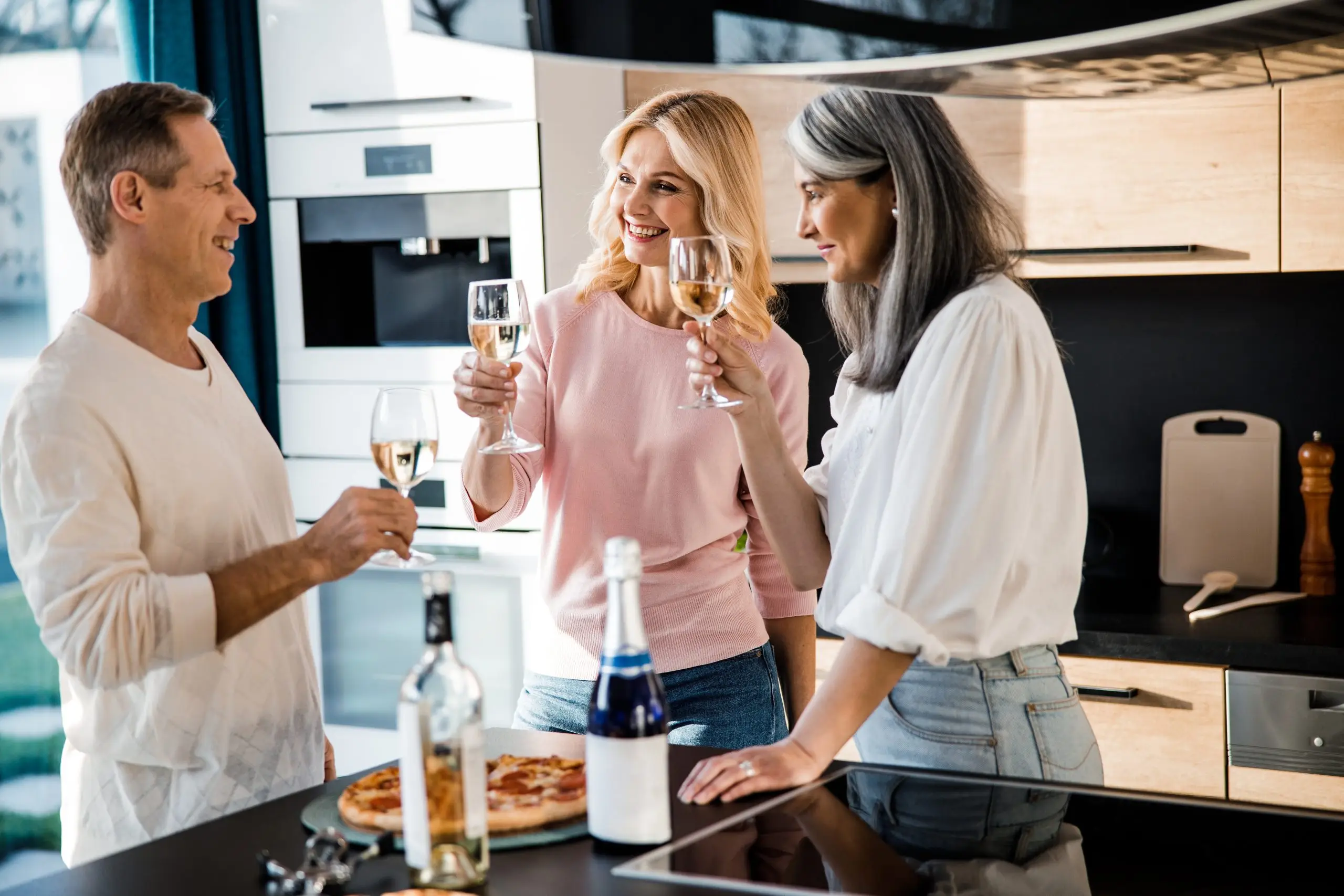 Happy man and women enjoying wine while standing together stock photo. Friendship and holidays concept
